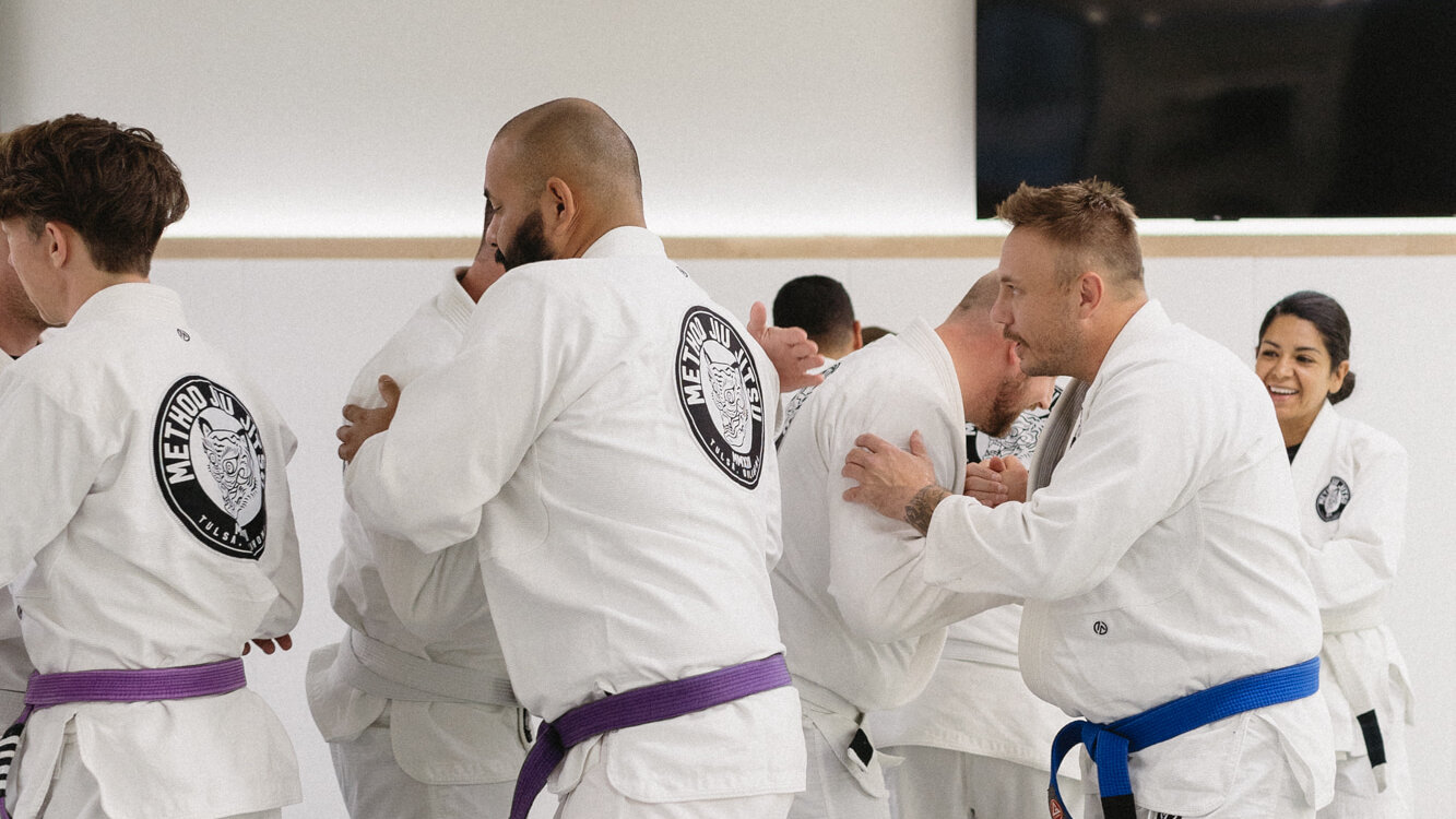 Adult BJJ students in white Method Jiu-Jitsu gis pairing up with training partners to start sparring rounds at Method Jiu-Jitsu in South Tulsa